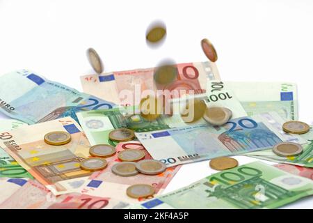 Euro Münzen fallen auf Euro Banknoten, Geldregen , hohe Kosten, Symbolbild Stockfoto