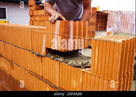 Ein Maurer beim Mauern eines Rohbaues in Massivbauweise. Ziegelmauer eines Einfamilienhauses Stockfoto