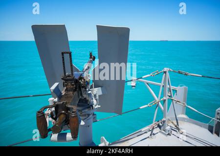 Farbbild eines automatisierten Maschinengewehrs auf dem Deck eines Militärschiffs auf See. Stockfoto