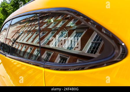 Ein schönes gelbes Lamborghini-Auto spiegelt die beeindruckenden traditionellen Backsteingebäude in diesem hochklassigen londoner Grosvenor Square wider Stockfoto