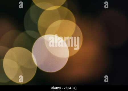 Großes, abstraktes Bokeh in Gelb aus Weihnachtslichtern auf schwarzem Hintergrund. Urlaubskonzept, Unschärfe Bokeh. Stockfoto