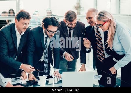 Gruppe von Mitarbeitern, die begeistert auf den Laptop-Bildschirm schauen Stockfoto