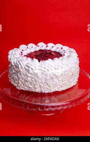 Kuchen mit Kirsche isoliert auf weißem Hintergrund. Stück Käsekuchen mit roten Früchten. Weiße Geburtstagstorte auf rotem Hintergrund. Kuchen mit Kirschmarmelade und Stockfoto