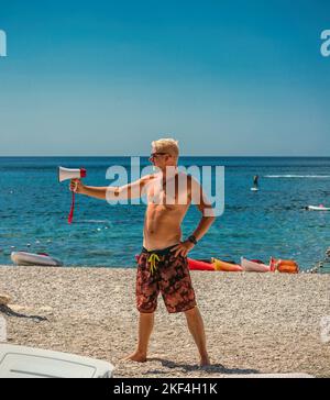 Der Helfer warnt vor dem Sturm über den Lautsprecher. Rettungsschwimmer arbeitet am Strand. Speicherplatz kopieren. Stockfoto