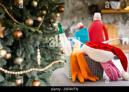 Reinigung vor Weihnachten. Mehrfarbige Reinigungsmittel. Schwämme, Lumpen und Spray mit festlichen Dekorationen vor dem Hintergrund Stockfoto