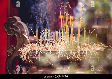 Nahaufnahme eines buddhistischen Tempelaltars mit brennendem Weihrauch und religiösen Dekorationen in Vietnam Stockfoto