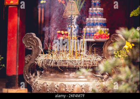 Nahaufnahme eines buddhistischen Tempelaltars mit brennendem Weihrauch und religiösen Dekorationen in Vietnam Stockfoto