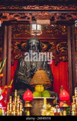 Eine vertikale Aufnahme eines buddhistischen Tempelaltars mit einer Konfuzius-Statue und Dekorationen in Vietnam Stockfoto