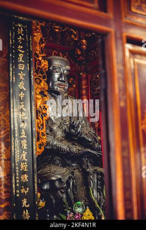 Eine vertikale Aufnahme eines buddhistischen Tempelaltars mit einer Konfuzius-Statue und Dekorationen in Vietnam Stockfoto