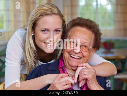 Ein Enkel besucht ihre Großmutter. Spass und Freude bei der Umarmung, Enkelin 30, 35, Jahre, Grossmutter 75, 80, Jahre, Enkelin, Grossmutter, Stockfoto