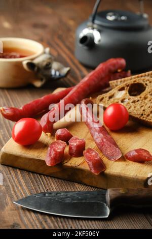 Trockene, dünne Schweinewurst, auf Scheiben auf Holzbrett geschnitten Stockfoto