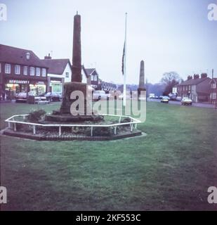 Meriden, das Zentrum von England, im Jahr 1980s. Dieses Bild zeigt das mittelalterliche Dorfkreuz auf dem Dorfgrün, ein 500 Jahre altes Artefakt der Klasse II. Das auch als „Sandsteinkreuz“ bekannte Denkmal besteht aus Sandstein und ist mit einer Gedenktafel versehen, die an Meriden's Status als „Zentrum von England“ erinnert. Im Hintergrund ist das 'Cyclists war Memorial' zu sehen. Das 1920 erbaute Gebäude erinnert an die im Ersten Weltkrieg getöteten Radfahrer. Stockfoto