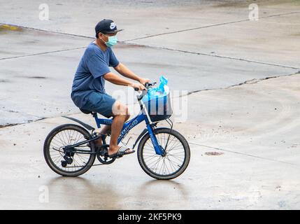 SAMUT PRAKAN, THAILAND, SEP 26 2022, Ein Mann fährt auf einem Fahrrad auf der nassen Straße. Stockfoto