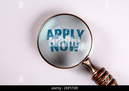 JETZT BEWERBEN. Text und Lupe auf weißem Hintergrund. Stockfoto