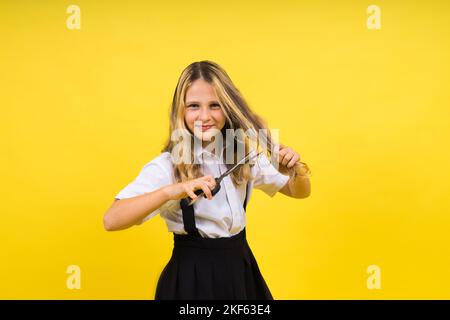 Teenager-Schulmädchen mit Schere, isoliert auf gelbem Hintergrund. Kinderkreativität, Kunst und Handwerk. Stockfoto