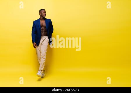 Typ in blauem Anzug auf gelbem Hintergrund. Hübscher, athletischer Mann in Jacke lächelnd Stockfoto