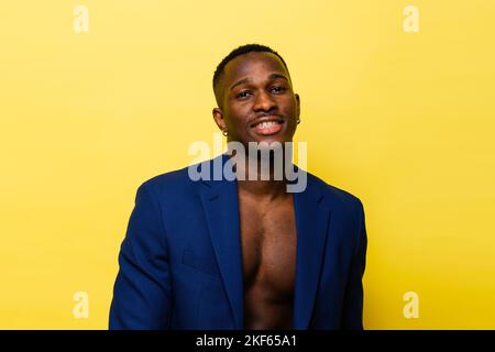 Typ in blauem Anzug auf gelbem Hintergrund. Hübscher, athletischer Mann in Jacke lächelnd Stockfoto