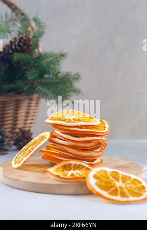 Weihnachtskomposition. Zusammensetzung aus trockenen Orangen und Fichtenzweigen mit Zapfen in einem Korb. Stockfoto