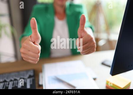 Geschäftsfrau mit Daumen nach oben im Büro und am Tisch mit Computer- und Finanzdokumenten. Stockfoto