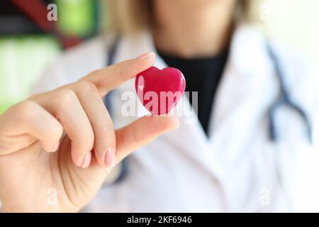 Kardiologin mit Stethoskop, das das rote Herz in der Hand hält. Stockfoto