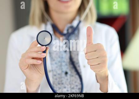 Beschnittene Ansicht einer Ärztin, die Stethoskop hält und Daumen nach oben zeigt. Stockfoto