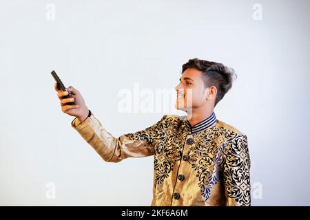 indischer Mann in ethnischer Kleidung mit Fernbedienung Stockfoto