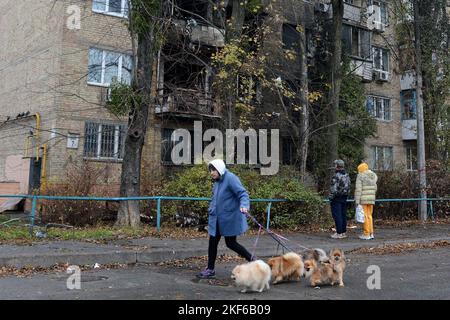 Nach einem massiven russischen Angriff auf Kiew führt eine Frau mit ihren Hunden an einem zerstörten Wohnhaus vorbei. Insgesamt hat Russland etwa 100 Marschflugkörper auf dem Territorium der Ukraine gestartet und infolgedessen wurden in vielen Städten des Landes Infrastrukturobjekte beschädigt. Stockfoto