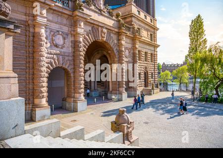 STOCKHOLM, SCHWEDEN - 10. JUNI 2022: Menschen, die in den Straßen von Stockholm durch das Parlamentsgebäude gehen, Schwedisch: Riksdagshuset, Gate, Stockholm, Schweden Stockfoto