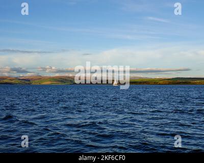 Segelboot vor der schottischen Küstenlandschaft mit sanften Hügeln, Firth of Clyde, nahe Isle of Bute, Schottland, Großbritannien. Stockfoto