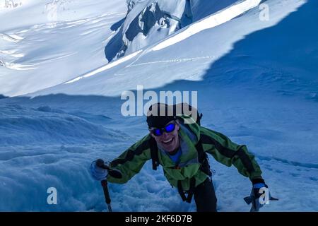 Beschreibung: Begeisterter Bergsteiger klettert mit Eisachsen über einen steilen Schneehang entlang der Jungfrau High Route. Jungfrau-Höhenweg, Berner Alpen, Stockfoto