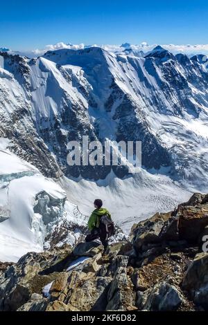 Beschreibung: Bergsteiger auf einer Felsküste genießt einen herrlichen Panoramablick auf die Tiefen des Rottals. Jungfrau-Höhenweg, Berner Alpen, Schweiz Stockfoto