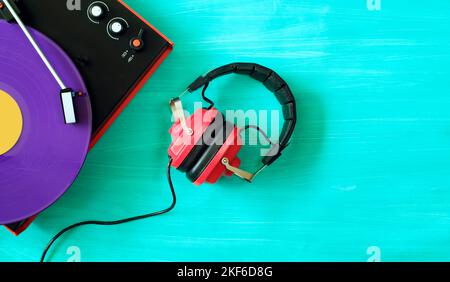 Plattenspieler aus den siebziger Jahren, Vintage-Kopfhörer und violett gefärbte Vinyl-Schallplatte. Renaissance analoger Vinyl-Schallplatten, freier Kopierraum, flaches Lay. Stockfoto