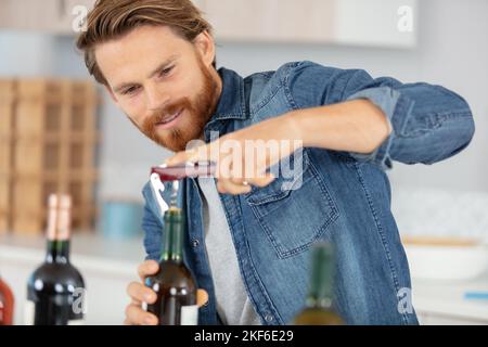 Männlicher Sommelier, offene Weinflasche mit Korkenzieher Stockfoto