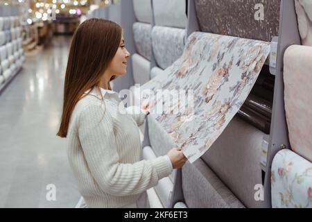 Junge Frau wählen Tapete im Baumarkt. Home Design und Renovierungskonzept. Stockfoto