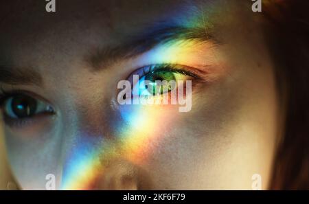 Eine junge Frau mit Regenbogenlicht auf ihrem Gesicht Stockfoto