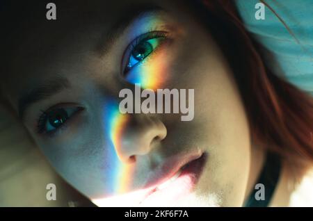 Eine junge Frau mit Regenbogenlicht auf ihrem Gesicht Stockfoto