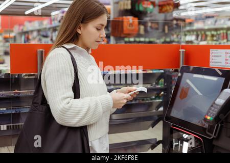 ?Customer Frau an Self-Service-Kasse im modernen Supermarkt nehmen Sie Bargeld Quittung Stockfoto