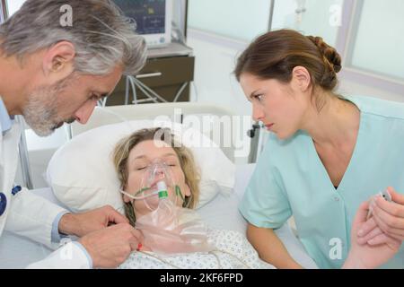 Männlicher Arzt mit Frau mit Sauerstoffmaske Stockfoto