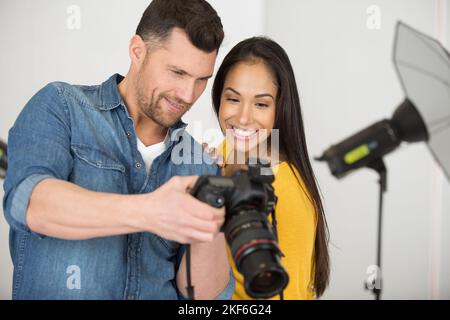 Fotograf und Model überprüfen Fotos auf dem Kamerabildschirm Stockfoto