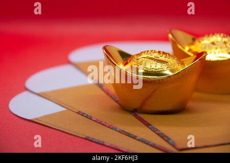 Nahaufnahme von Goldbarren auf gelben Päckchen. Chinesische Neujahrsfeier. Stockfoto