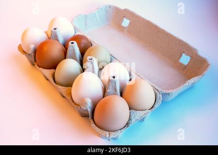 Auswahl an verschiedenen farbigen, frischen Hühnereiern. Hellbraun, weiß, dunkelbraun und grün. Eierbehälter aus recyceltem Material. Stockfoto