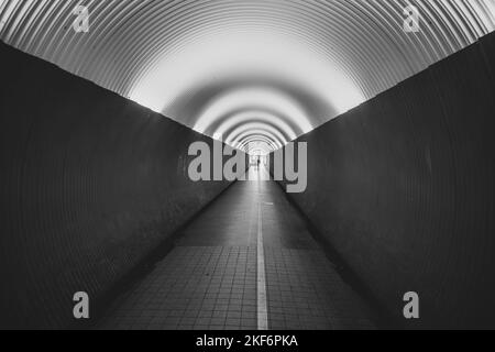 Menschen im Fußgängertunnel Brunkenberg in Stockholm, Schweden. Schwarzweiß-Bild. Stockfoto