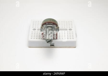 Ein variabler Widerstand oder Potentiometer mit Code B10K klebt auf einer kleinen Projektplatine auf weißem Hintergrund. Stockfoto