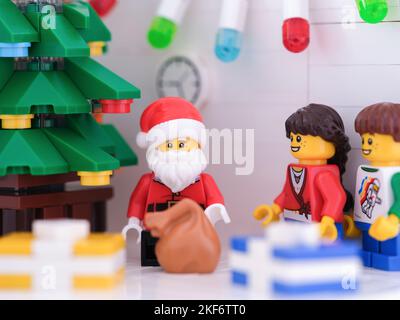 Tambov, Russische Föderation - 15. November 2022 Lego Weihnachtsmann und Kinder Minifiguren stehen in der Nähe eines Weihnachtsbaums mit Geschenken um ihn herum. Stockfoto