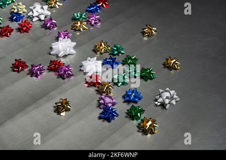 Geschenkpapiersterne in kräftigen Farben, strahlend weiß, Gold, Kobaltblau, Passionsrot, Formen von Mustern auf einer schimmernden grauen Textur Stockfoto