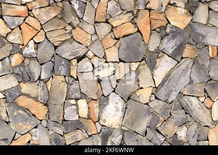 Ein grauer gelber Steinwall aus Steinplatten und Sandsteinplatten Hintergrund, holprige Steinwand Textur, Rocky Struktur Hintergrund Stockfoto