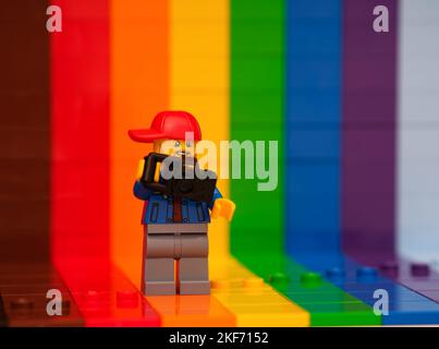 Tambov, Russische Föderation - 07. November 2022 Eine Minifigur von Lego-Fotografen mit einer Kamera, die vor einem Regenbogenhintergrund steht Stockfoto