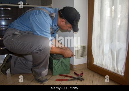 Handwerker in der Küche eines Hauses beim Reinigen des Filters der Belüftungsöffnung und des Belüftungslochs des Gaskochers. Stockfoto