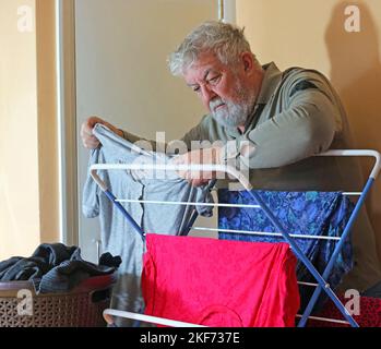 Älterer Mann, der sich zum Trocknen auf einem Wäscheständer oder Trockner aufgehängt hat. Stockfoto