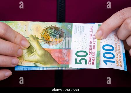 Die Frau hält Schweizer Geld, 100- und 50-Franken-Banknoten Stockfoto